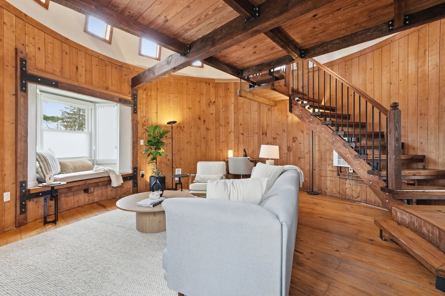 The Silo living room, with high curved windows and the staircase leading to the loft